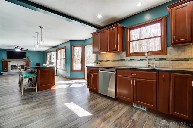 kitchen featuring visible vents, backsplash, stainless steel dishwasher, a ceiling fan, and a sink