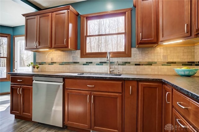 kitchen featuring dark countertops, a sink, backsplash, and stainless steel dishwasher