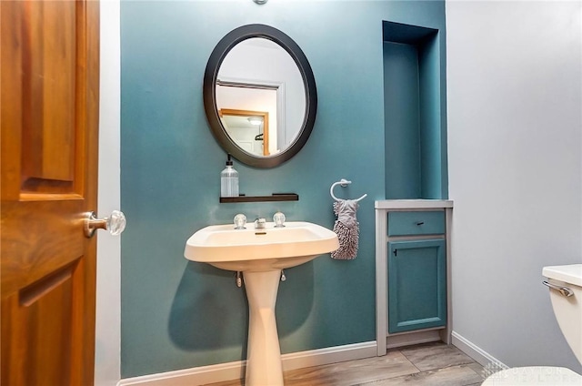 bathroom featuring a sink, toilet, baseboards, and wood finished floors