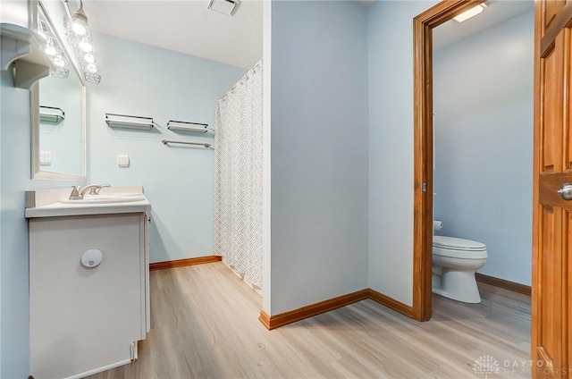 bathroom featuring vanity, toilet, wood finished floors, and baseboards