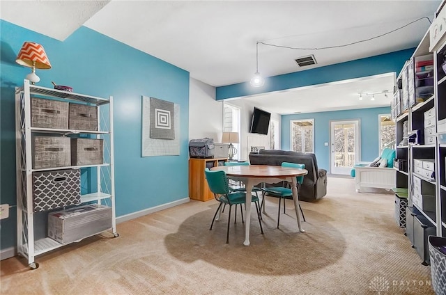 carpeted dining space featuring visible vents and baseboards