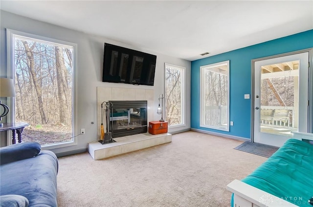 carpeted living room with a tiled fireplace, visible vents, and baseboards