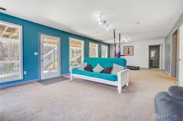 carpeted living room with visible vents, baseboards, and track lighting