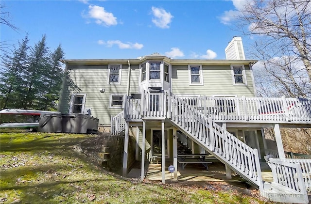 rear view of property with a chimney, stairs, and a deck