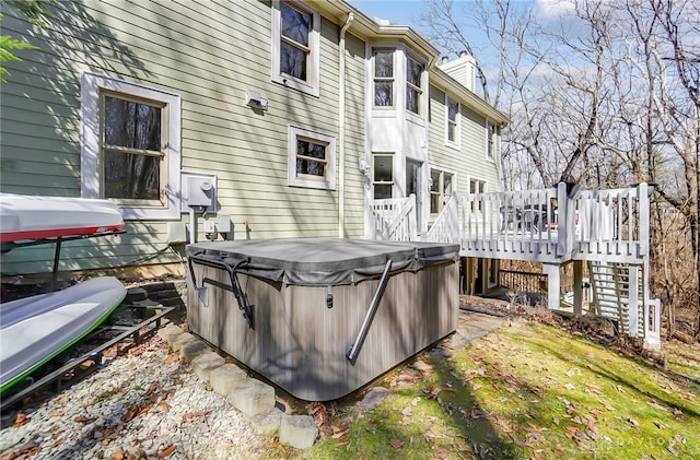 exterior space featuring a wooden deck, stairway, a chimney, and a hot tub