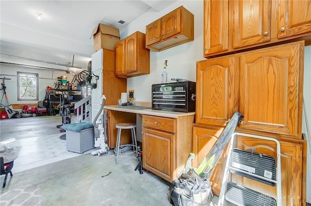 kitchen featuring brown cabinets, concrete floors, and light countertops