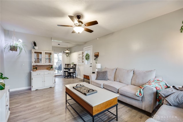 living area with light wood-style floors, baseboards, and ceiling fan