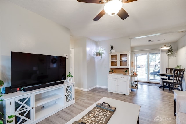 living area featuring ceiling fan, baseboards, and light wood-style flooring