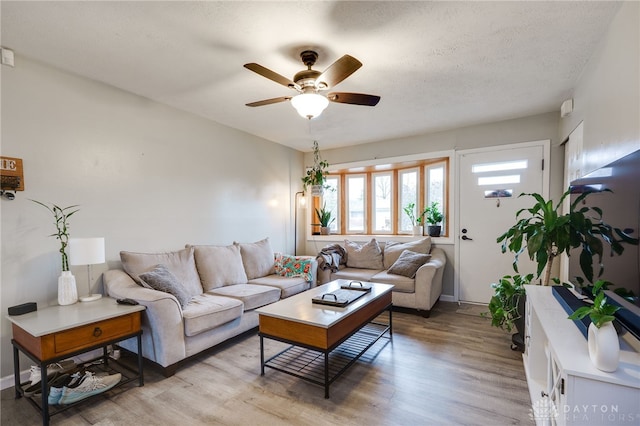 living area featuring a textured ceiling, light wood-type flooring, and ceiling fan