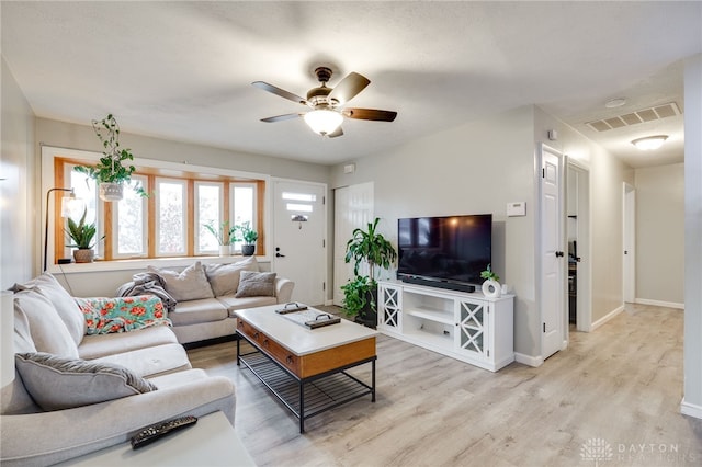 living area featuring visible vents, baseboards, light wood-type flooring, and a ceiling fan