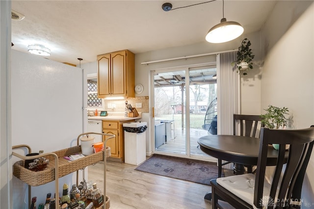 kitchen featuring light brown cabinets, pendant lighting, light countertops, decorative backsplash, and light wood-style floors