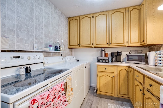 laundry room with independent washer and dryer, a sink, light wood-style floors, tile walls, and laundry area