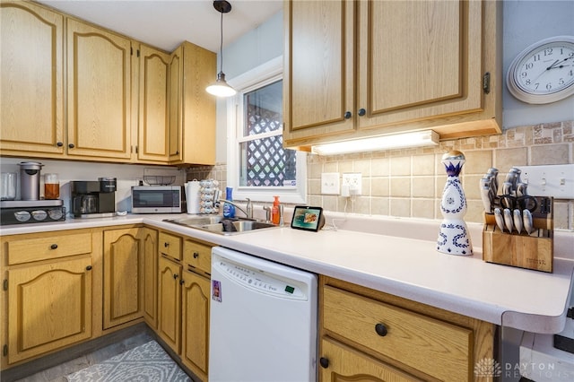 kitchen with a sink, stainless steel microwave, light countertops, decorative backsplash, and dishwasher