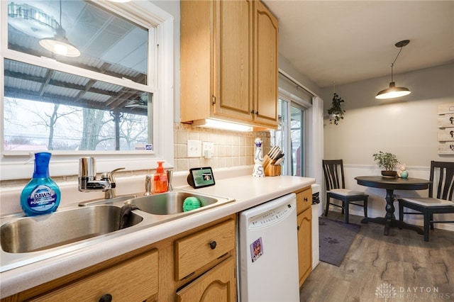 kitchen with light wood finished floors, decorative light fixtures, dishwasher, light countertops, and a sink