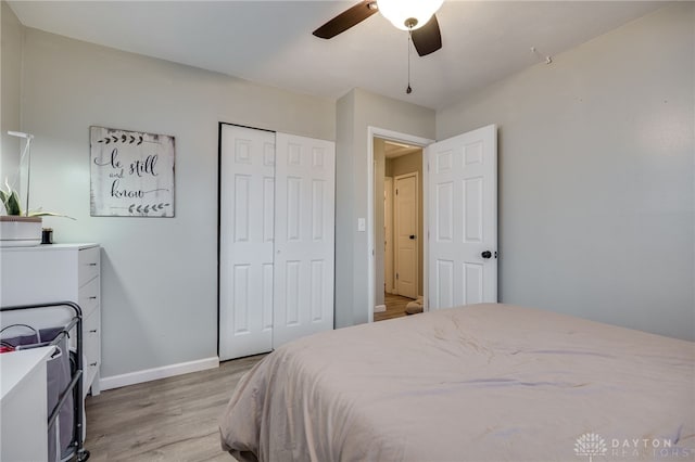 bedroom with ceiling fan, a closet, baseboards, and light wood-style flooring