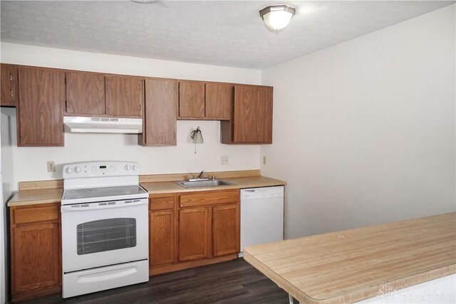 kitchen featuring white appliances, light countertops, under cabinet range hood, and a sink