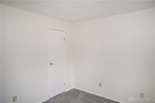 carpeted spare room featuring baseboards