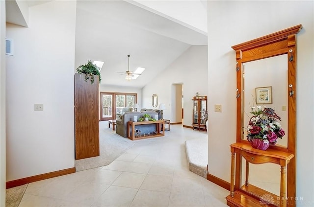 corridor featuring visible vents, baseboards, high vaulted ceiling, and a skylight