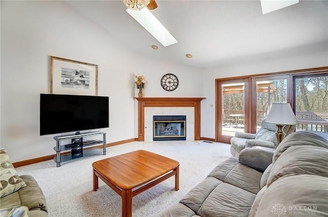 living area with baseboards, vaulted ceiling with skylight, carpet, and a fireplace