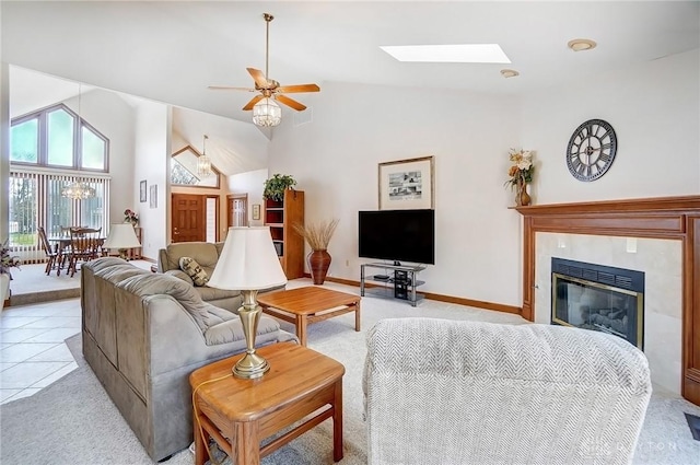 living room featuring light carpet, a glass covered fireplace, a skylight, and a ceiling fan