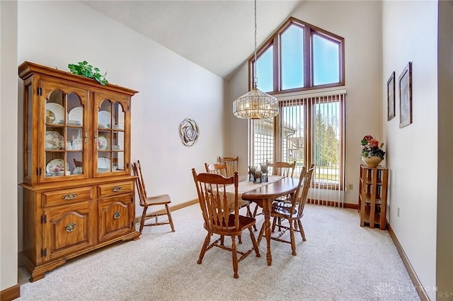 dining room with baseboards, light colored carpet, an inviting chandelier, and high vaulted ceiling