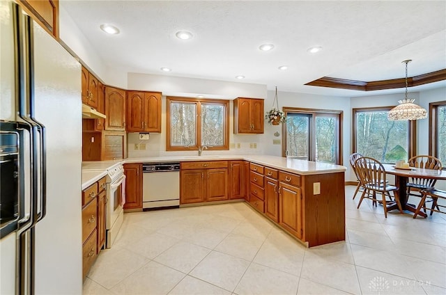 kitchen featuring brown cabinets, white appliances, a peninsula, and a sink