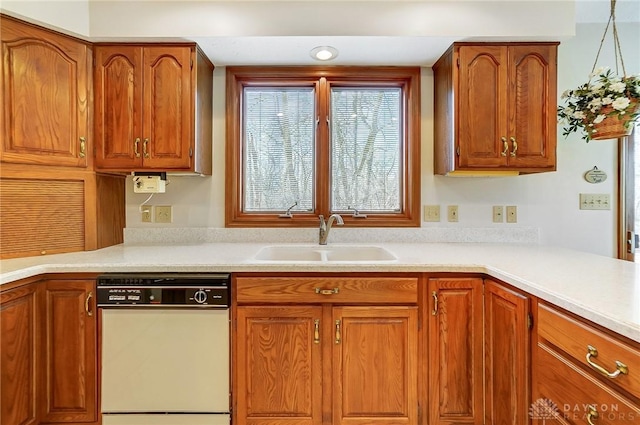 kitchen featuring dishwasher, light countertops, brown cabinets, and a sink