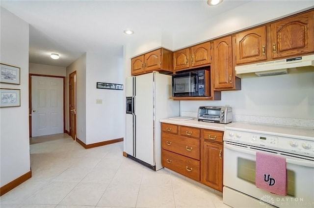 kitchen featuring baseboards, under cabinet range hood, light countertops, brown cabinetry, and white appliances