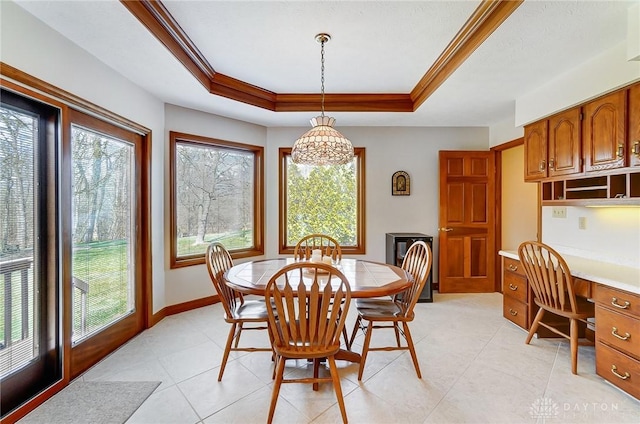 dining space with a wealth of natural light, a tray ceiling, baseboards, and crown molding