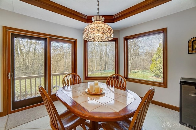 dining room with light tile patterned flooring, baseboards, crown molding, and a tray ceiling