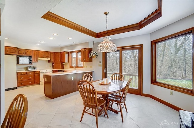 dining area with a tray ceiling, a toaster, baseboards, and ornamental molding