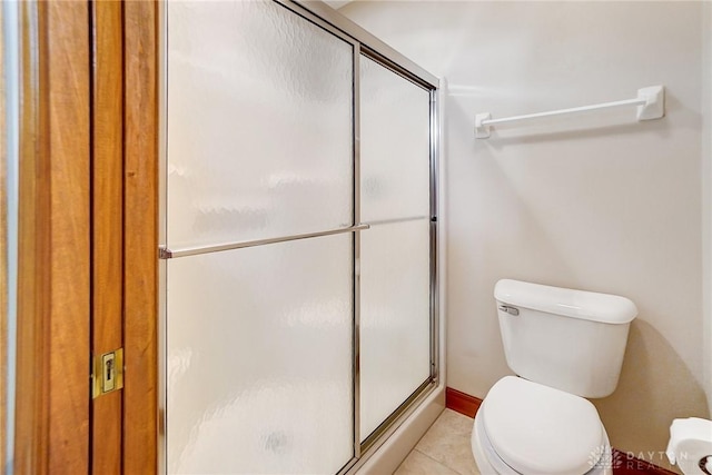 bathroom with tile patterned floors, toilet, and a stall shower