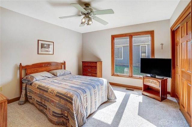 bedroom with visible vents, light colored carpet, a ceiling fan, and baseboards