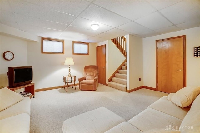 carpeted living area featuring a paneled ceiling, baseboards, and stairs