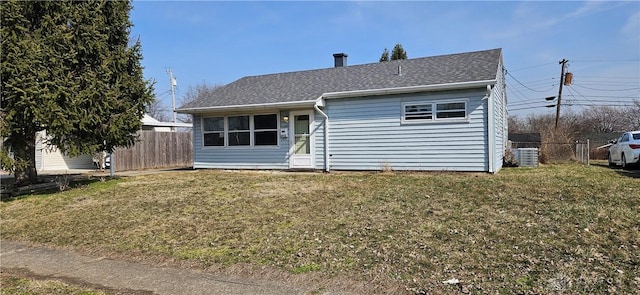 ranch-style home with roof with shingles, a front lawn, and fence