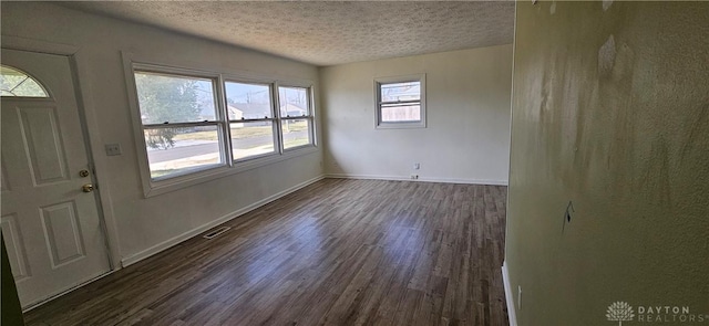 empty room featuring baseboards, dark wood-type flooring, and a textured ceiling