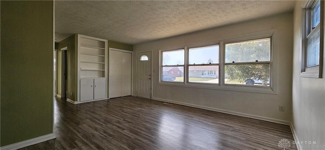 interior space with dark wood finished floors, baseboards, and a textured ceiling