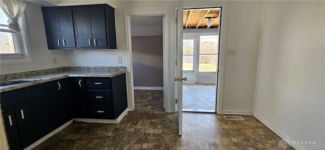 kitchen featuring a sink, visible vents, baseboards, and dark cabinets