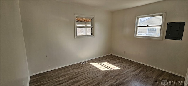 unfurnished room with dark wood finished floors, electric panel, baseboards, and visible vents