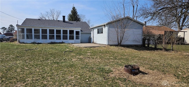 back of house featuring fence, an outdoor fire pit, a lawn, a sunroom, and an outbuilding