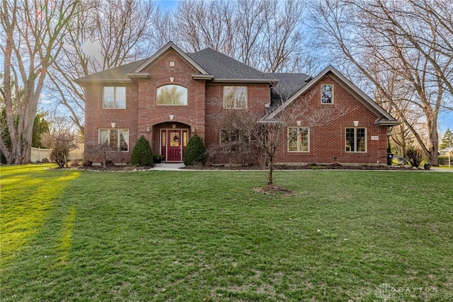 view of front of property with a front yard, brick siding, and roof with shingles