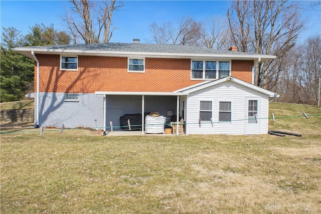 rear view of house with brick siding and a yard