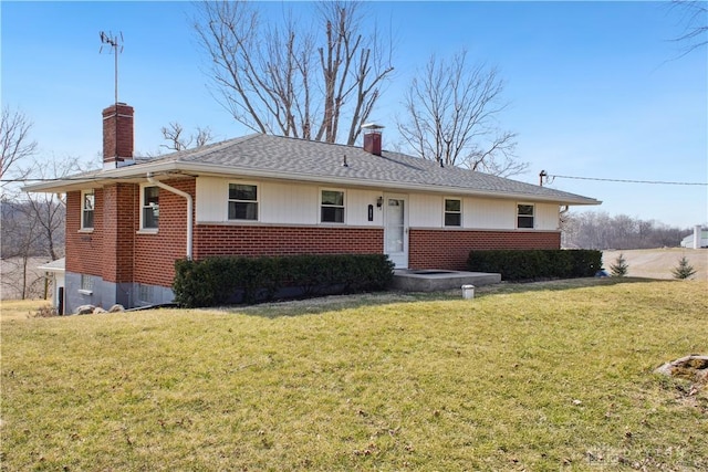 view of front of home featuring brick siding, a chimney, and a front yard