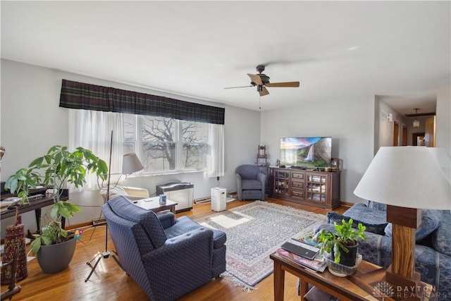 living area featuring a ceiling fan, wood finished floors, and baseboards