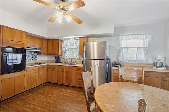 kitchen featuring under cabinet range hood, black appliances, light countertops, and a sink