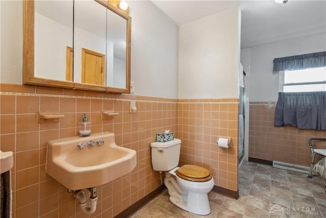 bathroom with a sink, toilet, a wainscoted wall, and walk in shower