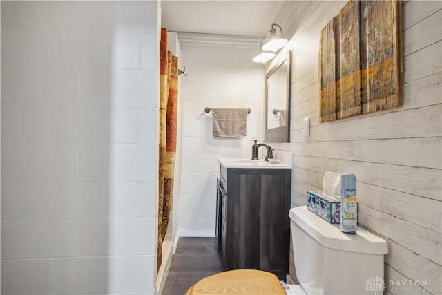 full bath with vanity, concrete block wall, toilet, and a shower with curtain