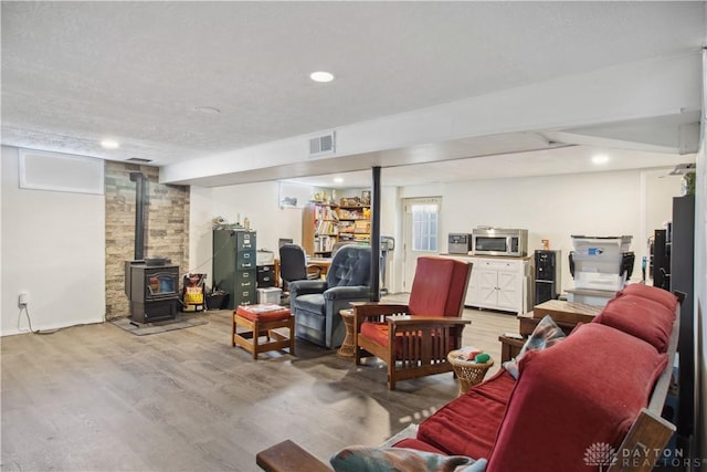 living area featuring visible vents, recessed lighting, light wood-type flooring, and a wood stove