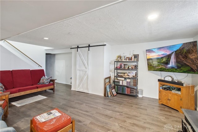 living area featuring stairway, a textured ceiling, a barn door, and wood finished floors