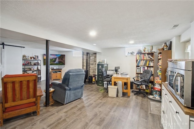 interior space featuring visible vents, light wood-type flooring, and a textured ceiling